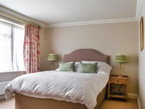 a bedroom with a bed with white sheets and green pillows at An Croke in Higham