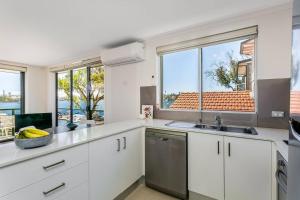 een keuken met witte kasten en een groot raam bij STG38 - stunning waterfront apartment - Drummoyne in Sydney