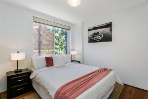 ein weißes Schlafzimmer mit einem Bett und einem Fenster in der Unterkunft STG38 - stunning waterfront apartment - Drummoyne in Sydney