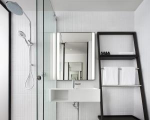 a bathroom with a sink and a shower with a mirror at Little National Hotel Canberra in Canberra