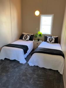 - 2 lits dans une petite chambre avec fenêtre dans l'établissement FISHERMANS’DELIGHT, à Whangaroa