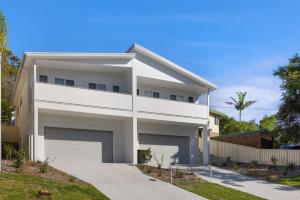 une maison blanche avec un garage dans l'établissement Bentley Beach Villa, à Nelson Bay