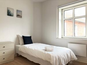 una camera bianca con un letto e una finestra di Spacious 3 Bedroom Apartment With 2 Common Rooms a Vejle