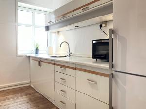 cocina con armarios blancos, fregadero y nevera en Spacious 3 Bedroom Apartment With 2 Common Rooms en Vejle