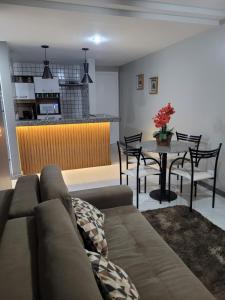 uma sala de estar com um sofá e uma mesa com cadeiras em Apart Guarapari Residence - Areia Preta em Guarapari