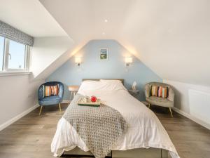 a attic bedroom with a bed and two chairs at The Haven in Milford Haven