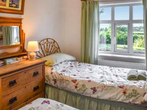 a bedroom with a bed and a dresser and a window at 1 Brandiston Barn Cottage in Cawston