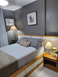 um quarto com uma cama e uma mesa com um candeeiro em Apart Guarapari Residence - Areia Preta em Guarapari