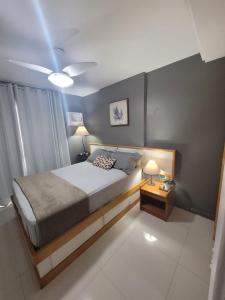 1 dormitorio con 1 cama y 1 mesa con 2 lámparas en Apart Guarapari Residence - Areia Preta, en Guarapari