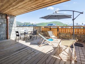 a deck with a table and chairs and an umbrella at Appartement Huez, 2 pièces, 4 personnes - FR-1-645-40 in LʼHuez