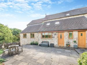 a stone house with a patio with a table and chairs at Rowan House in Carsington