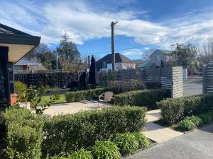 un jardin avec des buissons et un banc sur un trottoir dans l'établissement 20A Chepstow Avenue, Chch, à Christchurch