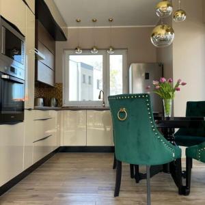 a kitchen with a green chair and a table at Dom „Pod lasem” w Ustce in Ustka