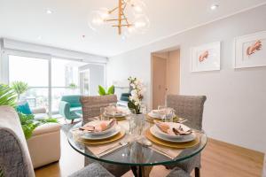 a dining room with a glass table and chairs at Skyliving Towers Apartments - Perú in Lima