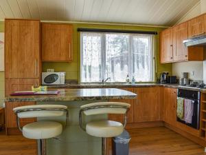 a kitchen with wooden cabinets and a counter with stools at Buckland Lodge in Pentridge