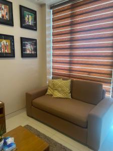 - un canapé brun dans le salon avec une fenêtre dans l'établissement C2 Mactan, à Punta Engaño
