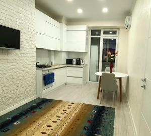 een keuken met witte kasten en een tafel en een televisie bij Bernardazzi residence in Chişinău