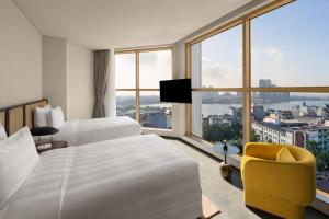 ハノイにあるL7 WEST LAKE HANOI By LOTTEのベッド2台と大きな窓が備わるホテルルームです。