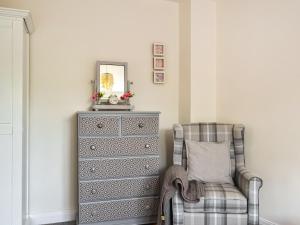 a dresser and a chair next to a dresser at Ivy Cottage in North Coates