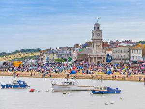 um grupo de pessoas em uma praia com barcos na água em Hillrise em Herne Bay