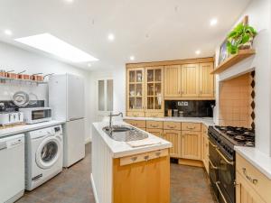 a kitchen with white appliances and wooden cabinets at Workshop Cottage in Rawcliffe