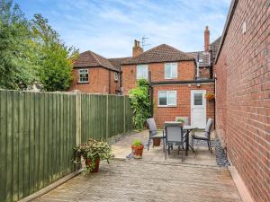 un patio con una valla, una mesa y sillas en Workshop Cottage, en Rawcliffe