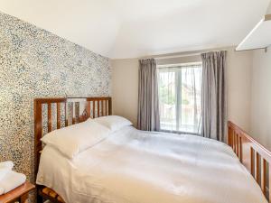 1 dormitorio con cama blanca y ventana en Workshop Cottage, en Rawcliffe