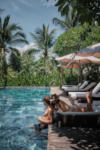 um grupo de pessoas sentadas na piscina de um resort em Hoi An Eco Lodge & Spa em Hoi An
