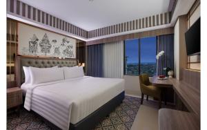 um quarto com uma cama, uma secretária e uma janela em The Alana Hotel & Conference Center Malioboro Yogyakarta by ASTON em Yogyakarta