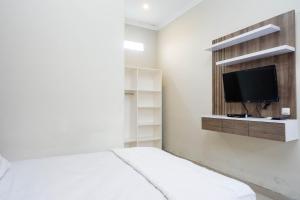 Un dormitorio con una cama y un televisor de pantalla plana. en RedDoorz at Berlian Homestay Malioboro Yogyakarta, en Yogyakarta