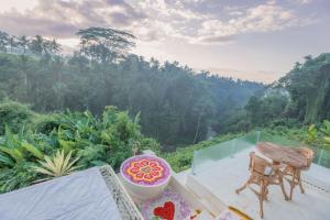 einen Balkon mit einem Tisch und einer Schüssel Blumen in der Unterkunft Villa Cella Bella Ubud in Ubud