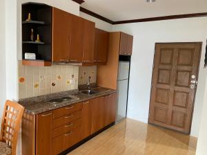 - une cuisine avec des placards en bois, un évier et une porte dans l'établissement View Talay 5 at Nong Apartment, à Pattaya (sud)