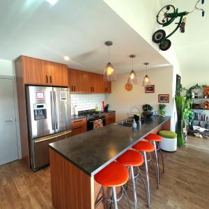 a kitchen with an island with orange bar stools at Hawea Heaven: Superking beds + Hot Tub + Mountain in Wanaka