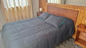 1 dormitorio con 1 cama con cabecero de madera en Cabańas Nordicas futrono, en Futrono
