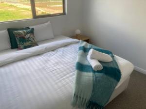 a white bed with a blue and white blanket on it at Kincaid@234 in Wagga Wagga