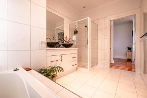 a white bathroom with a tub and a mirror at Ensorcelled - Freycinet Holiday Houses in Swansea +33 photos