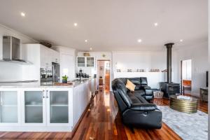 a kitchen and living room with a black leather couch at Ensorcelled - Freycinet Holiday Houses in Swansea