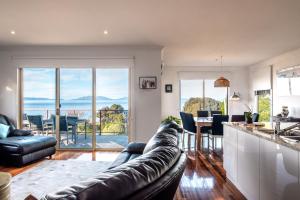 a living room with a couch and a kitchen with a view at Ensorcelled - Freycinet Holiday Houses in Swansea