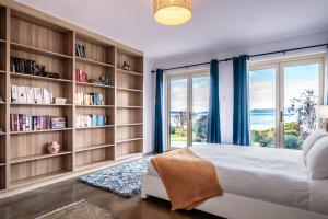 a bedroom with book shelves and a bed with a window at Ensorcelled - Freycinet Holiday Houses in Swansea