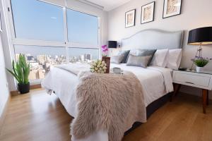 Schlafzimmer mit einem weißen Bett und einem großen Fenster in der Unterkunft Skyliving Towers Apartments - Perú in Lima