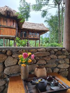 uma parede de pedra com uma mesa e flores sobre ela em Xoi Farmstay - Homefarm in Lam Thuong valley em Lung Co (1)