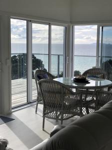 une salle à manger avec une table et des chaises et l'océan dans l'établissement Hosts on the Coast Sea Blue Hideaway, à Kuaotunu