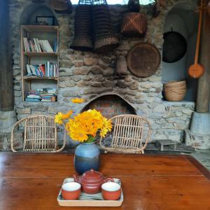 a table with a vase with flowers in front of a stone fireplace at Xoi Farmstay - Homefarm in Lam Thuong valley in Lung Co (1)