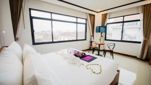 1 dormitorio con 1 cama con sábanas blancas y ventanas en Sisombat Plaza Hotel, en Vang Vieng