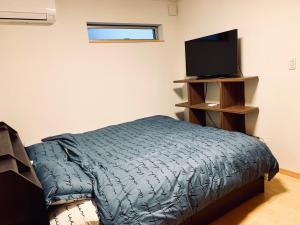 Schlafzimmer mit einem Bett und einem Flachbild-TV in der Unterkunft K.House in Tokio