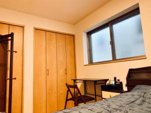 1 dormitorio con cama, escritorio y ventana en K.House, en Tokio
