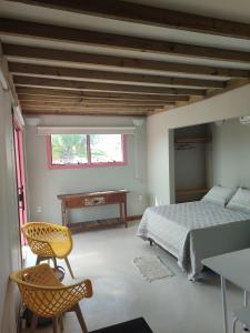 1 dormitorio con cama, mesa y ventana en EcoFlats Caraiva en Caraíva