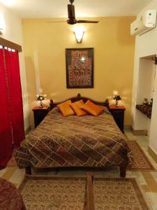 ein Schlafzimmer mit einem Bett mit orangefarbenen Kissen darauf in der Unterkunft Killa Bhawan Lodge in Jaisalmer