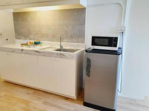 a kitchen with a sink and a refrigerator with a microwave at Baan 192 in Bangkok