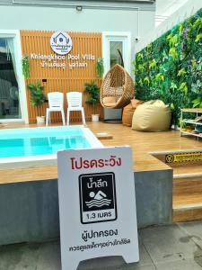 um sinal em frente a uma piscina com cadeiras em Khiangkhoo Pool Villa ChiangKhan - เคียงคู่พูลวิลล่าเชียงคาน em Chiang Khan
